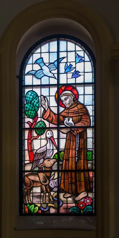 A stained glass window in a church depicting St Francis of Assisi with birds and animals.