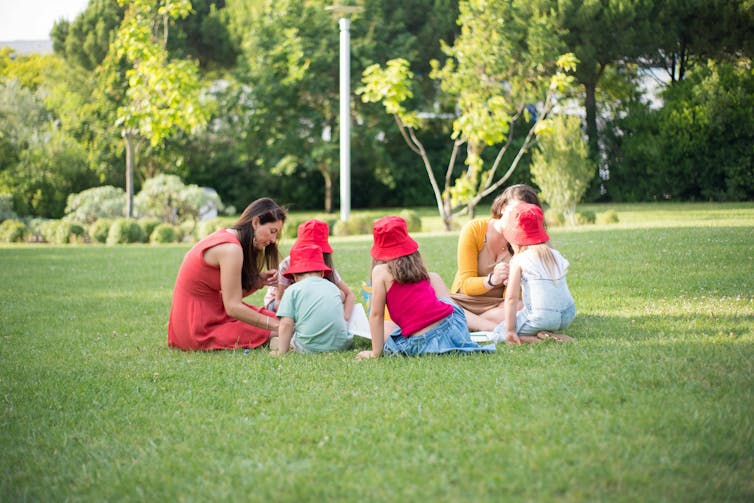 Group of People Sitting on Green Grass Field
