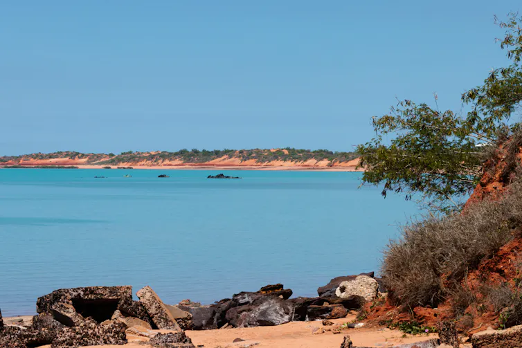 A flat blue bay bordered by red desert.