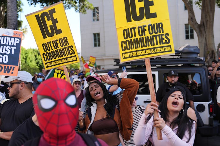 Protesters hold banners reading