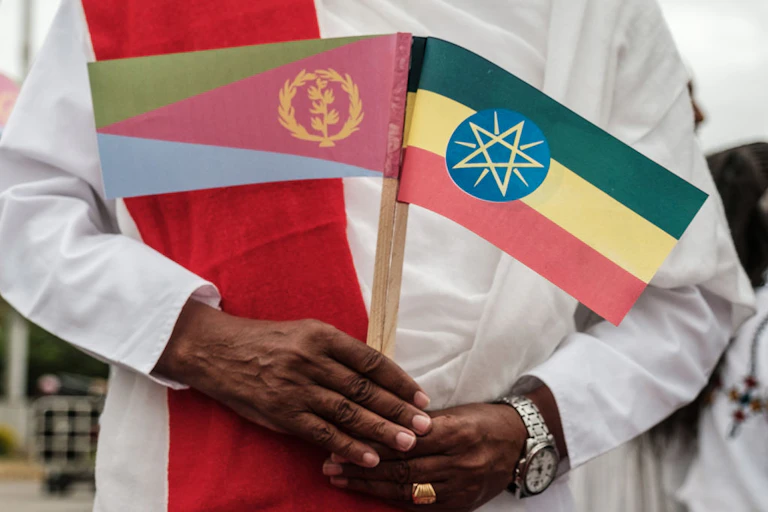 A man holds miniature national flags of Eritrea (left) and Ethiopia.