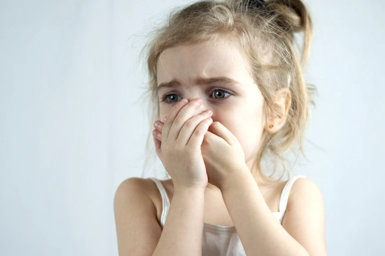 Niña con cara de dolor.