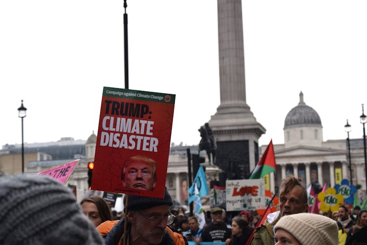 Donald Trump's financial arguments aren't new and don't justify the removal of local weather insurance policies 1 Someone is holding a banner that reads: