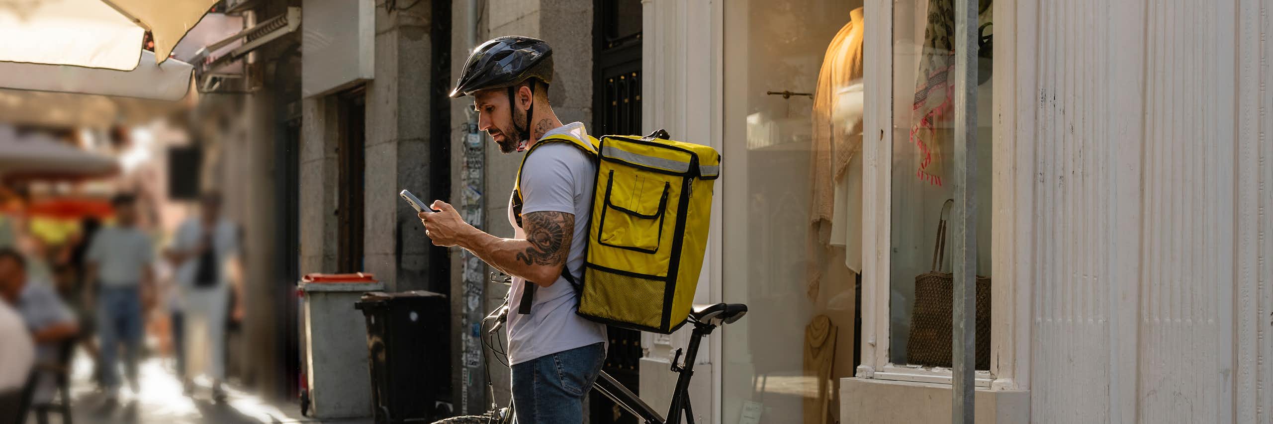 Repartidor mirando un móvil con su bicicleta estacionada