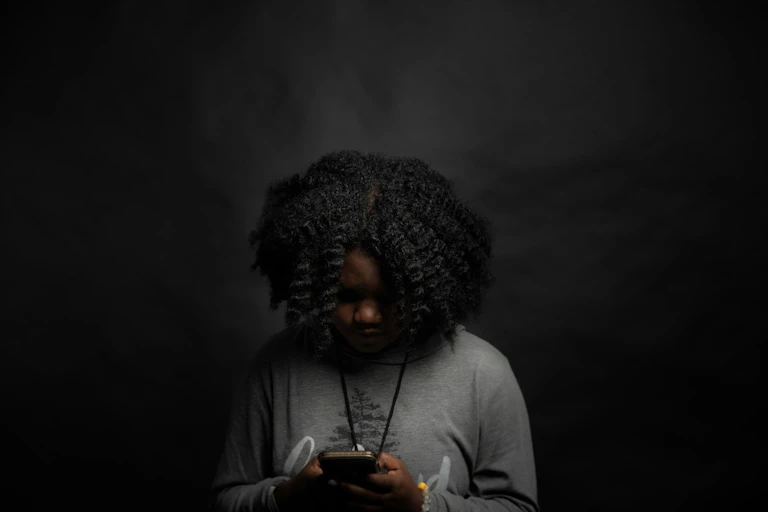 A Black woman looking through her smart phone.