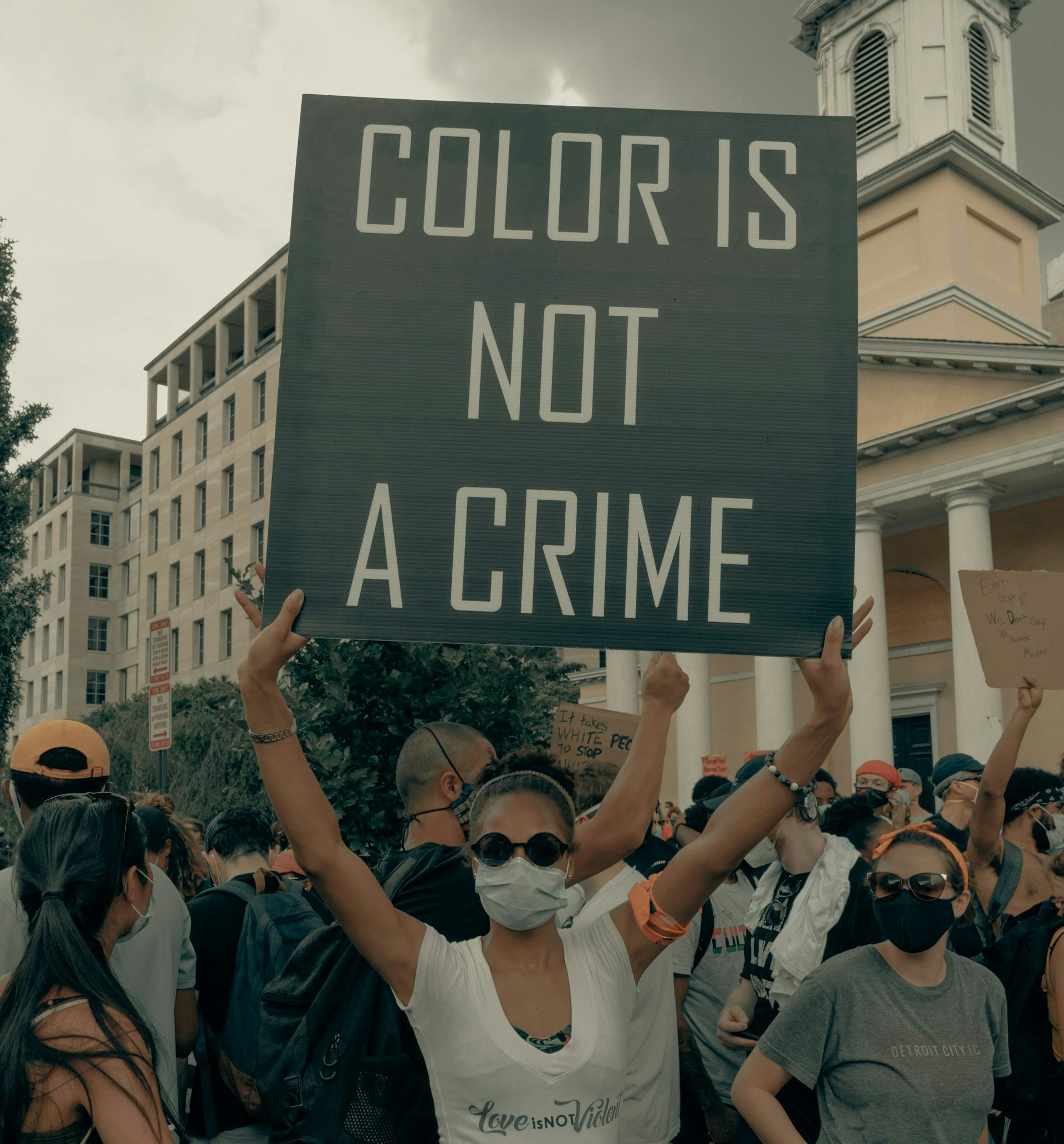 A racialized woman holding signage at a protest.