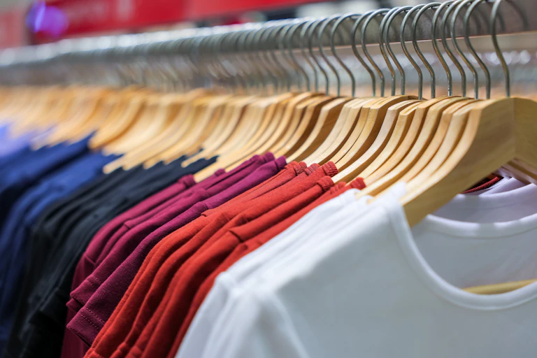 row of colourful t-shirts hanging on a rack in a shop.