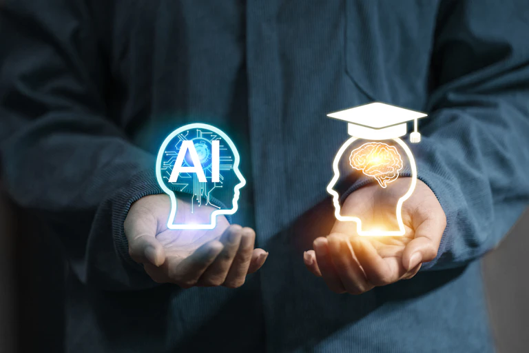 A person has an illuminated graphic in each hand - one shows a person's head that says 'AI' on the inside, and the other shows a person's head wearing a graduation cap.