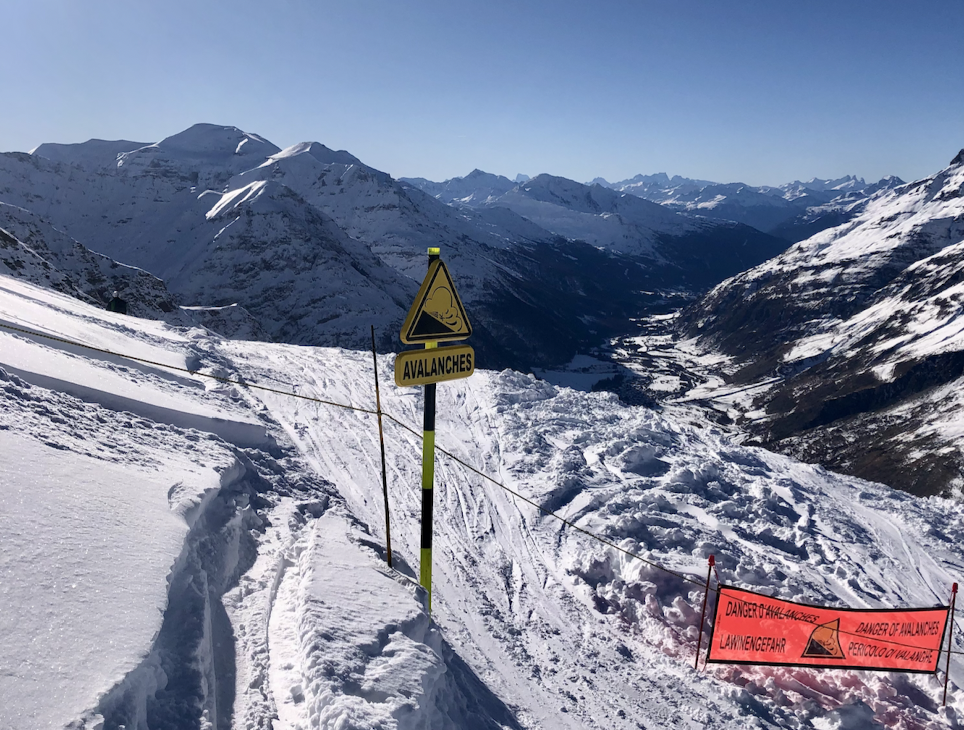 a snow-covered mountain area with a warning sign about avalances.