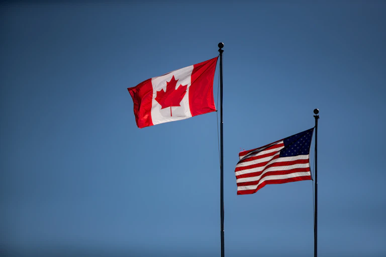 Canadian and U.S. flags fly on poles