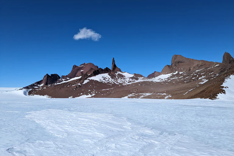 Rocky mountains rising from white snow into clear blue sky.