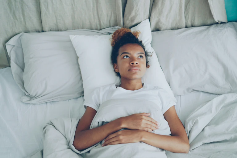 Woman lies with eyes open in bed