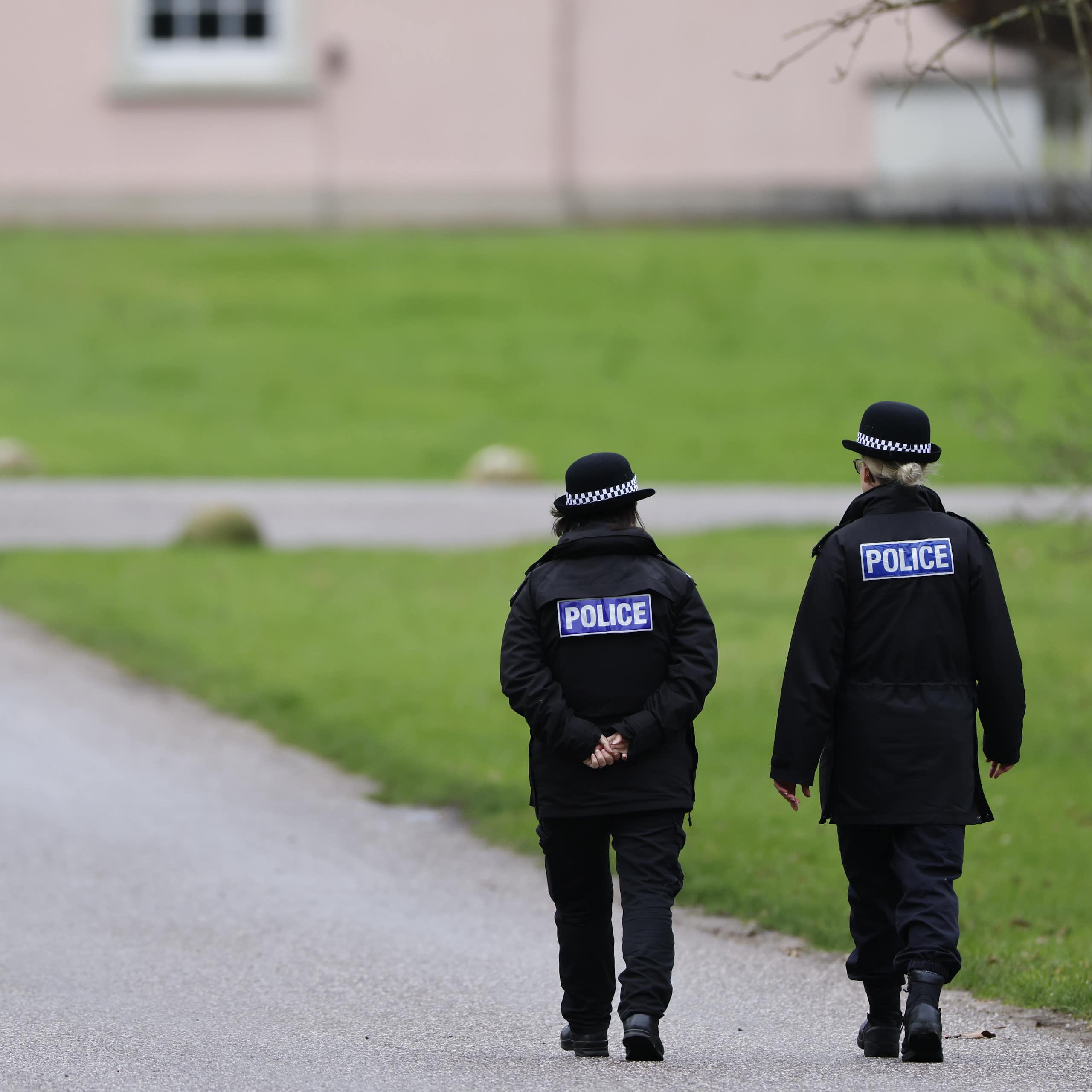 View from behind of two police officers walking down a path