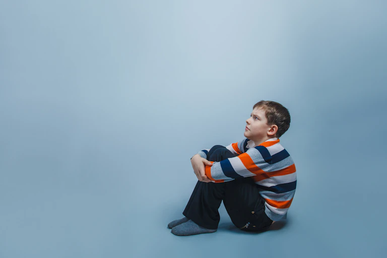A seated child, staring into the distance.