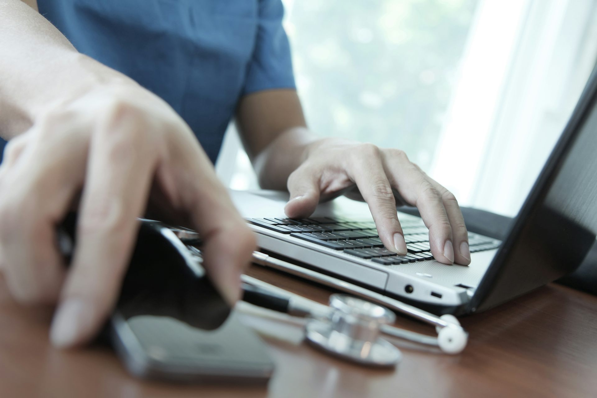 Doctor working with laptop computer in medical setting.