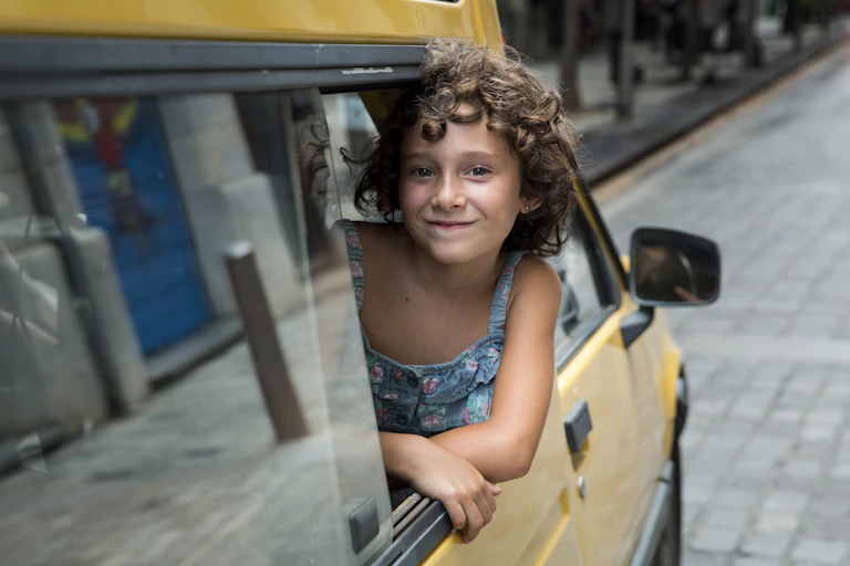 A child leans out of a yellow car window.