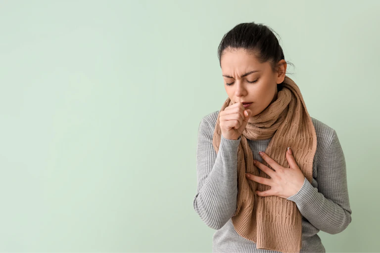 A woman coughing into her hand.