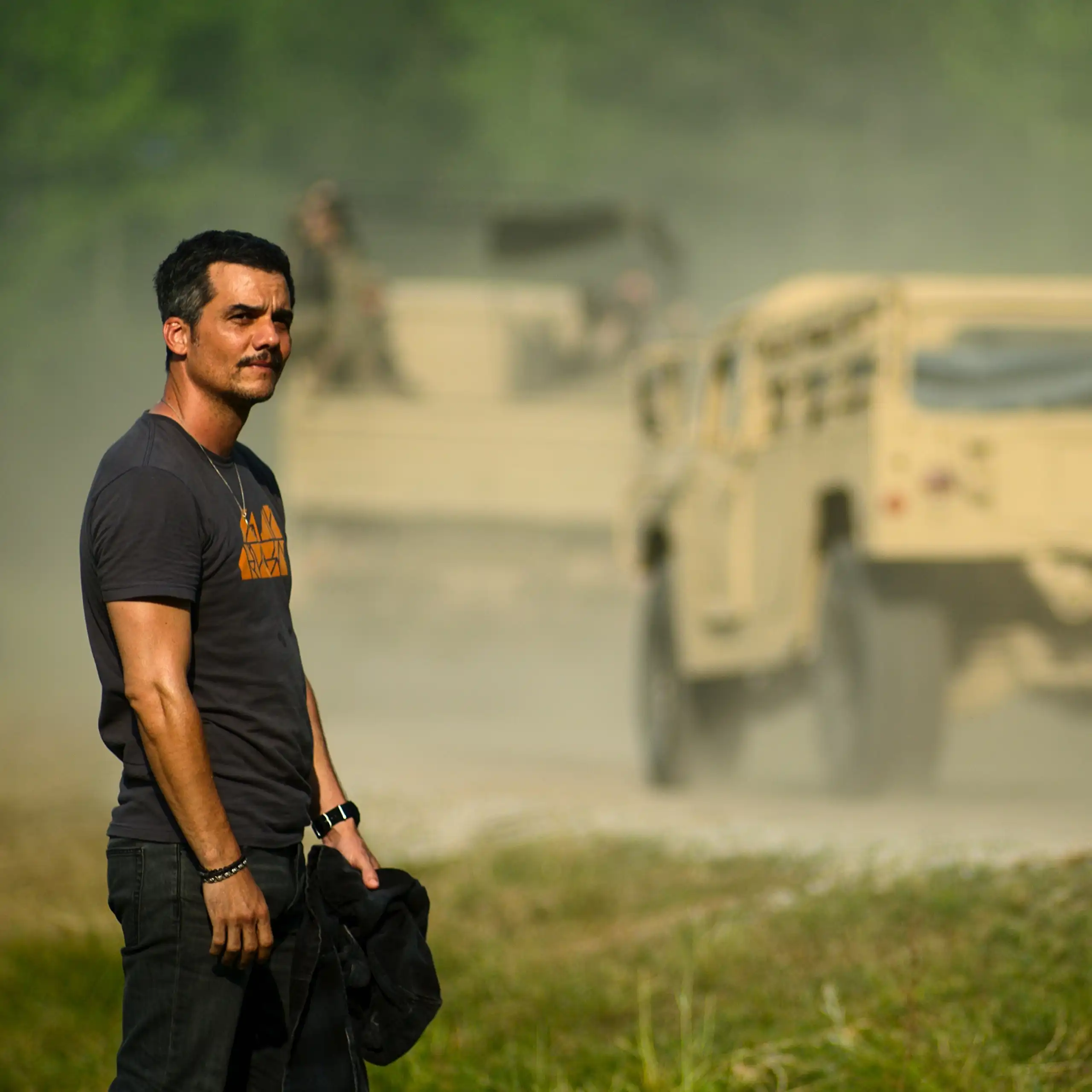 Un hombre mira una carretera por la que pasan camiones militares.
