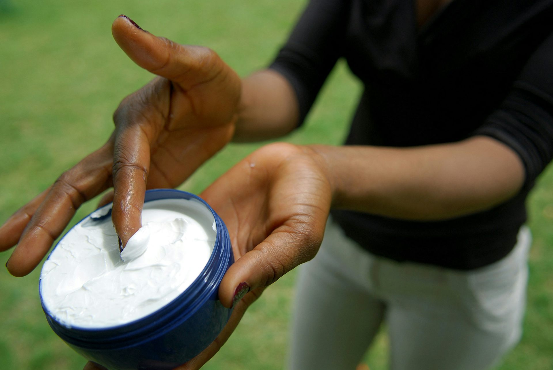 A woman holding a tub of skin-lightening cream.