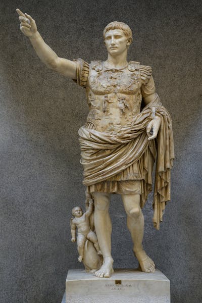 stone statue of a man in draping toga raising one arm, with one leg forward