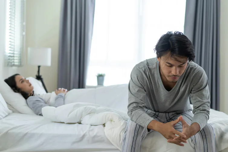 A couple on their bed having a disagreement.