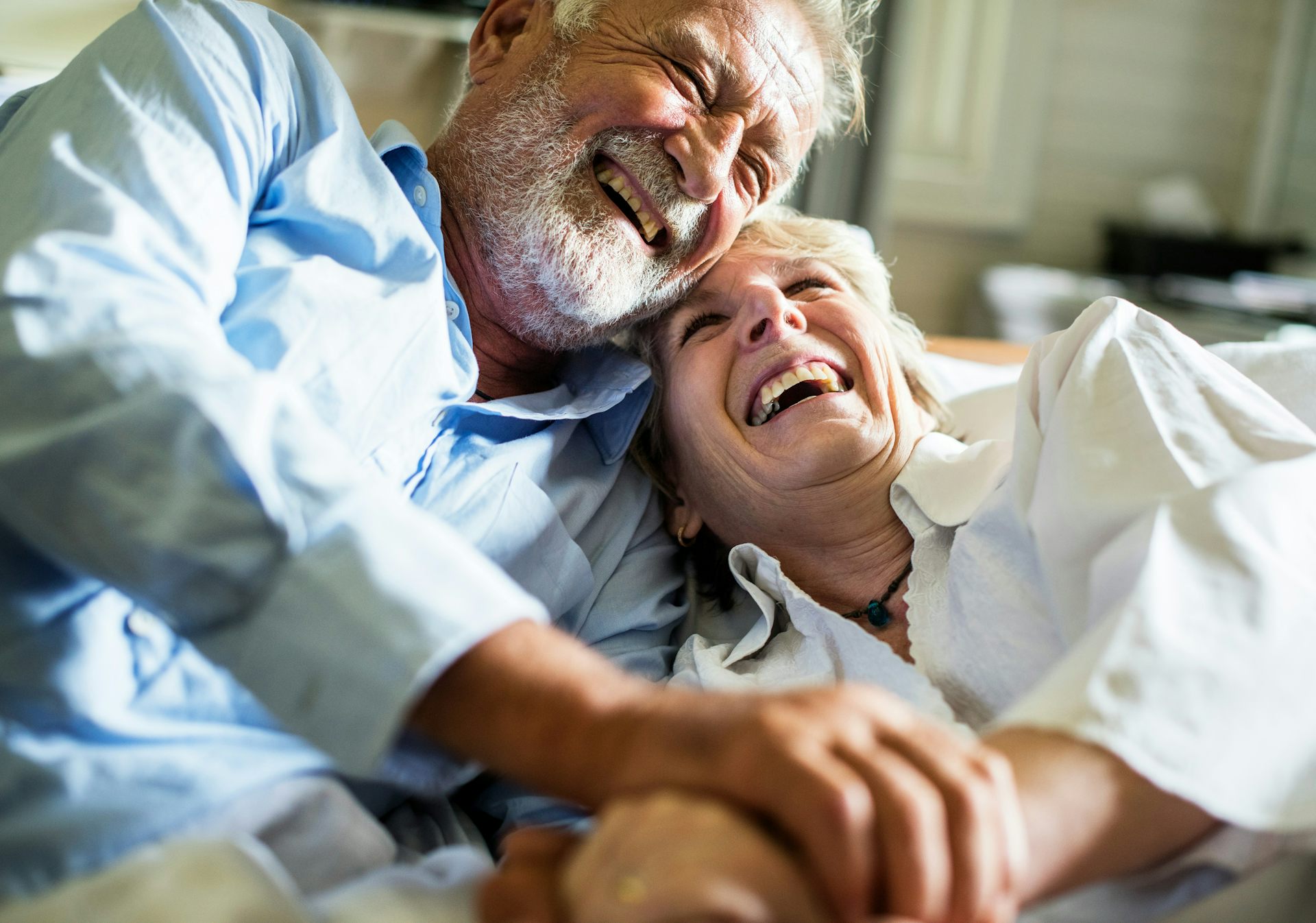 Pareja de ancianos abrazándose y riendo.