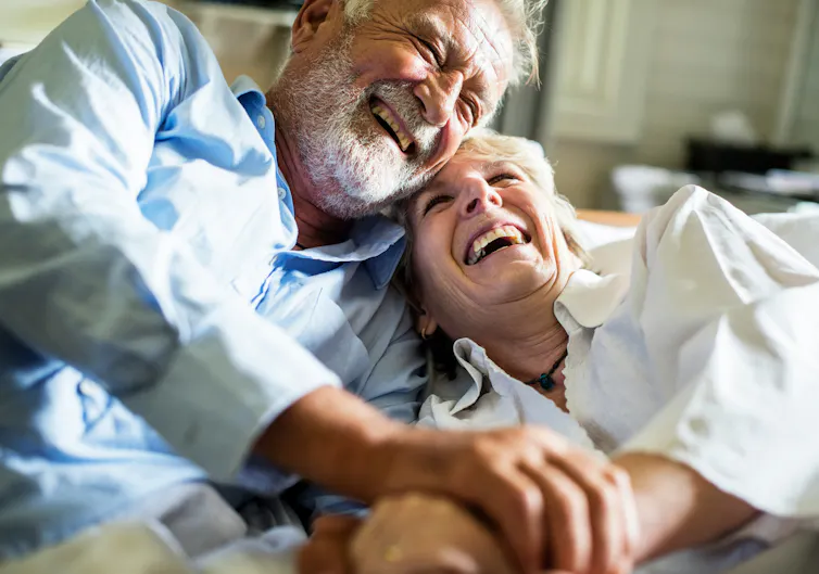 An older couple embracing and laughing.