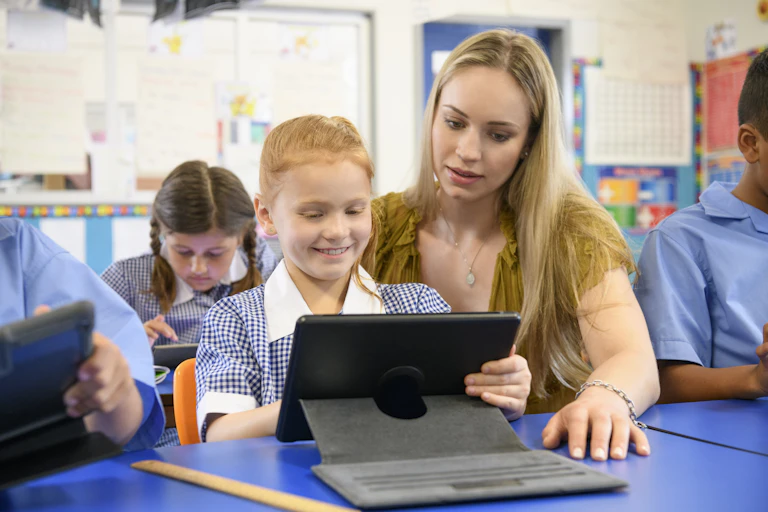 Woman sitting with child in classroom, working with a tablet