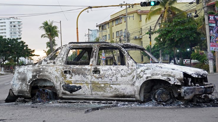 A burned car is seen on a street.