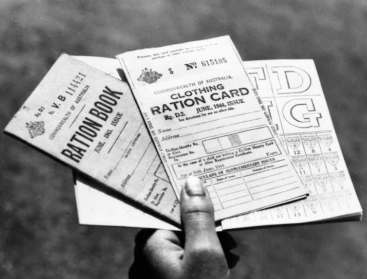 Black-and-white photograph of a hand holding several wartime ration cards.