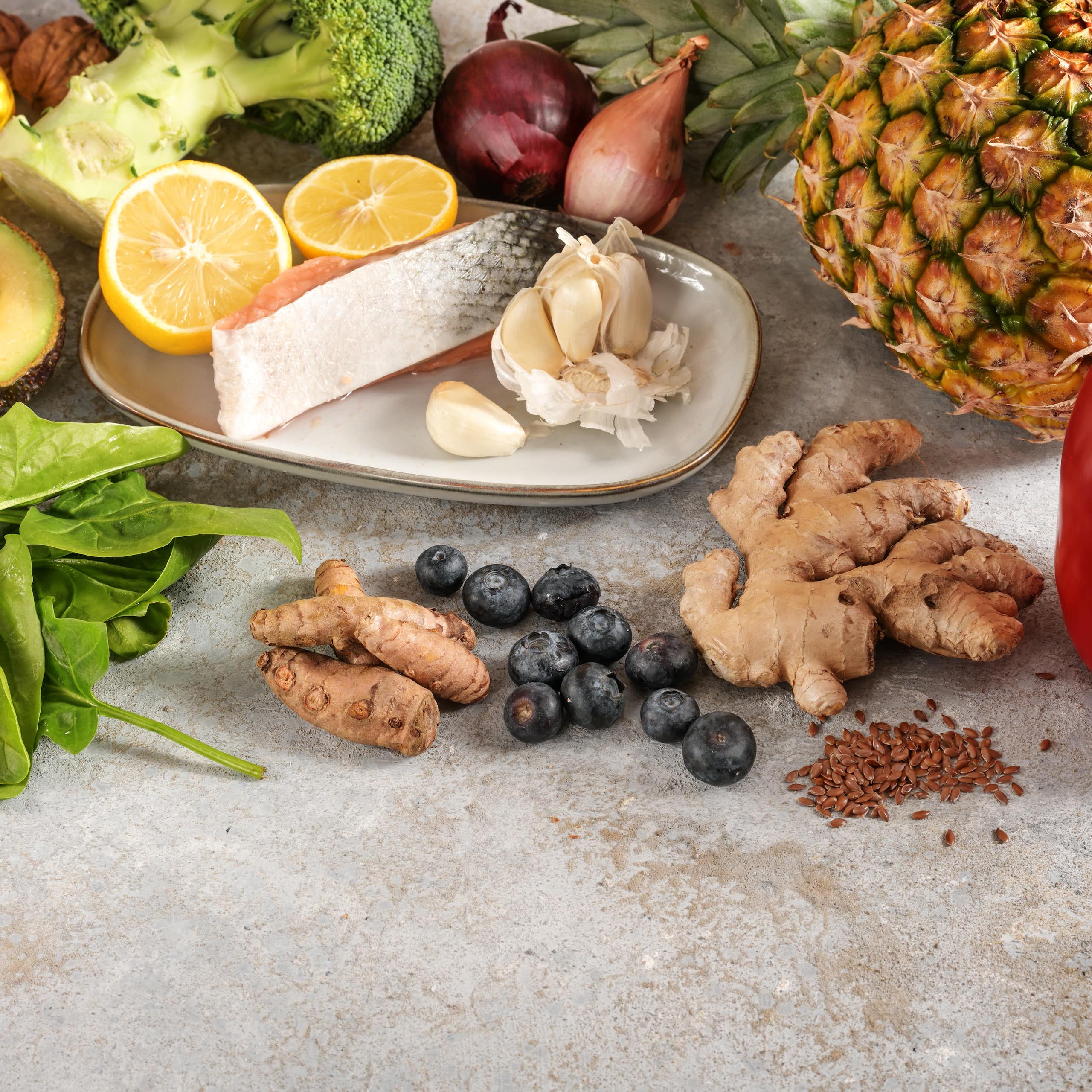 Una taula parada amb salmó, all, pinya, bròcoli, ceba, nabius, espinacs i li