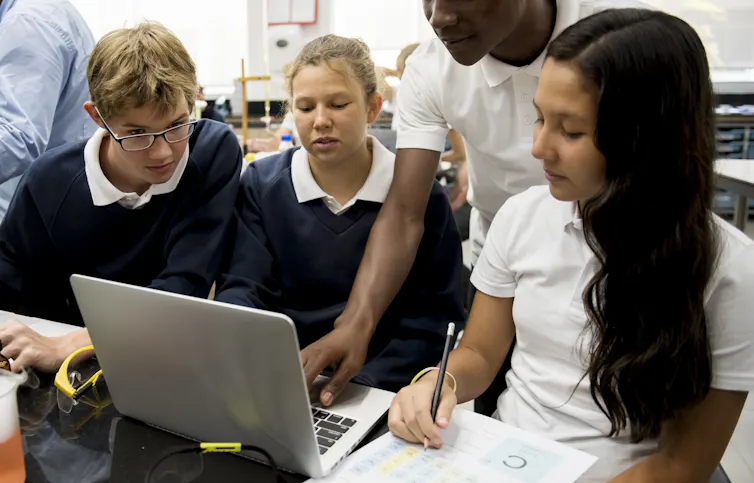 Children in uniform looking at laptop
