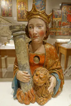 A small, painted statue of crowned woman clutching a pillar in one arm and a small lion in the other.