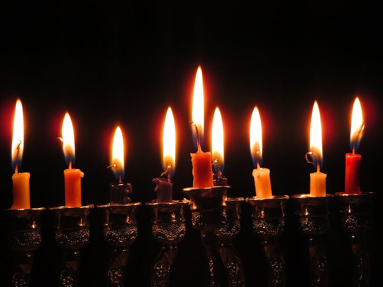 Nine lit candles against a dark background.