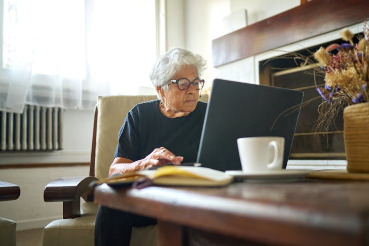 an older woman uses a laptop computer at a table