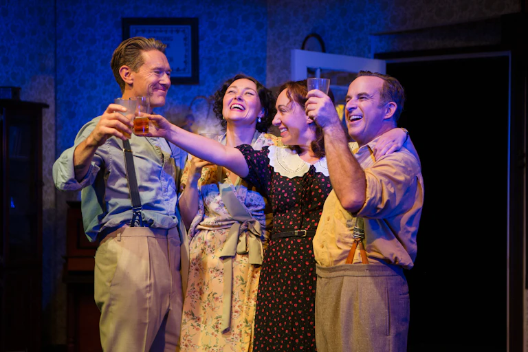 Production image: four characters share in a toast.