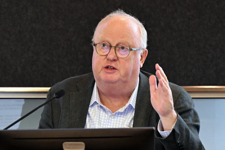 A man in glasses speaking in front of a microphone