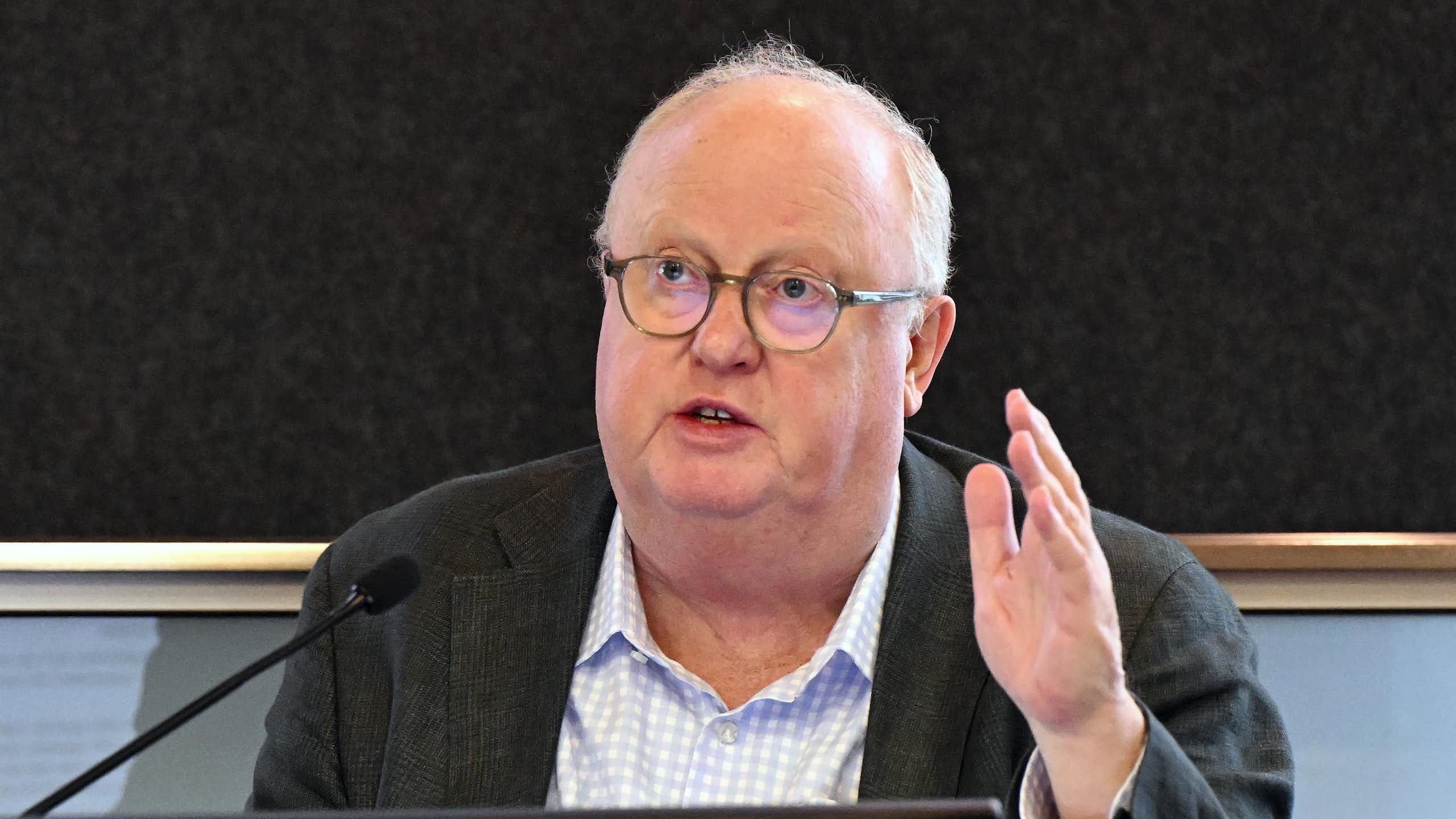 A man in glasses speaking in front of a microphone