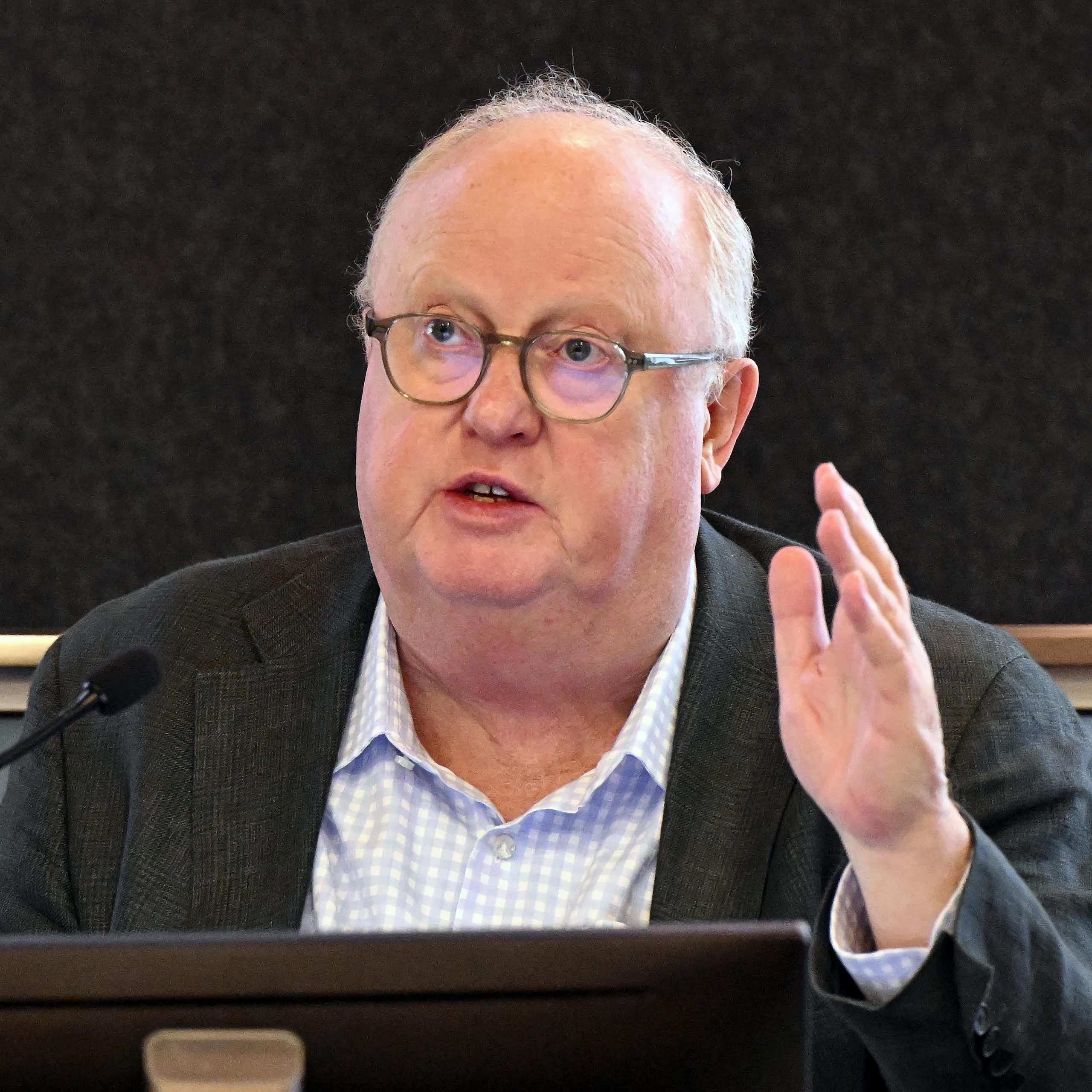A man in glasses speaking in front of a microphone