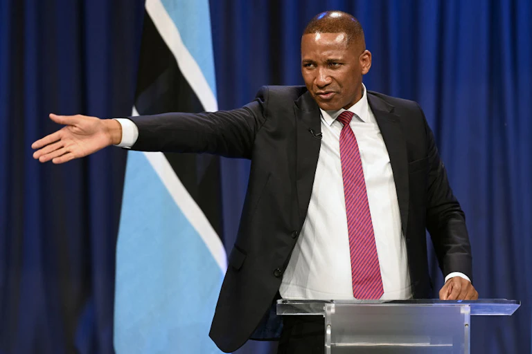 A man in a suit and tie gestures from a podium