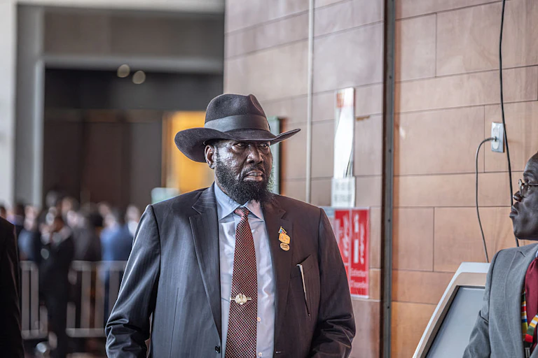 A man in suit and tie, wearing a cowboy hat, walking towards the camera