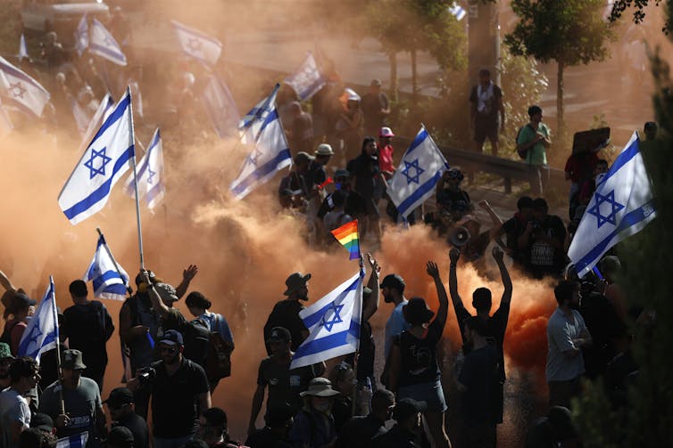 Israeli demonstrators wave Israel flags during a protest.