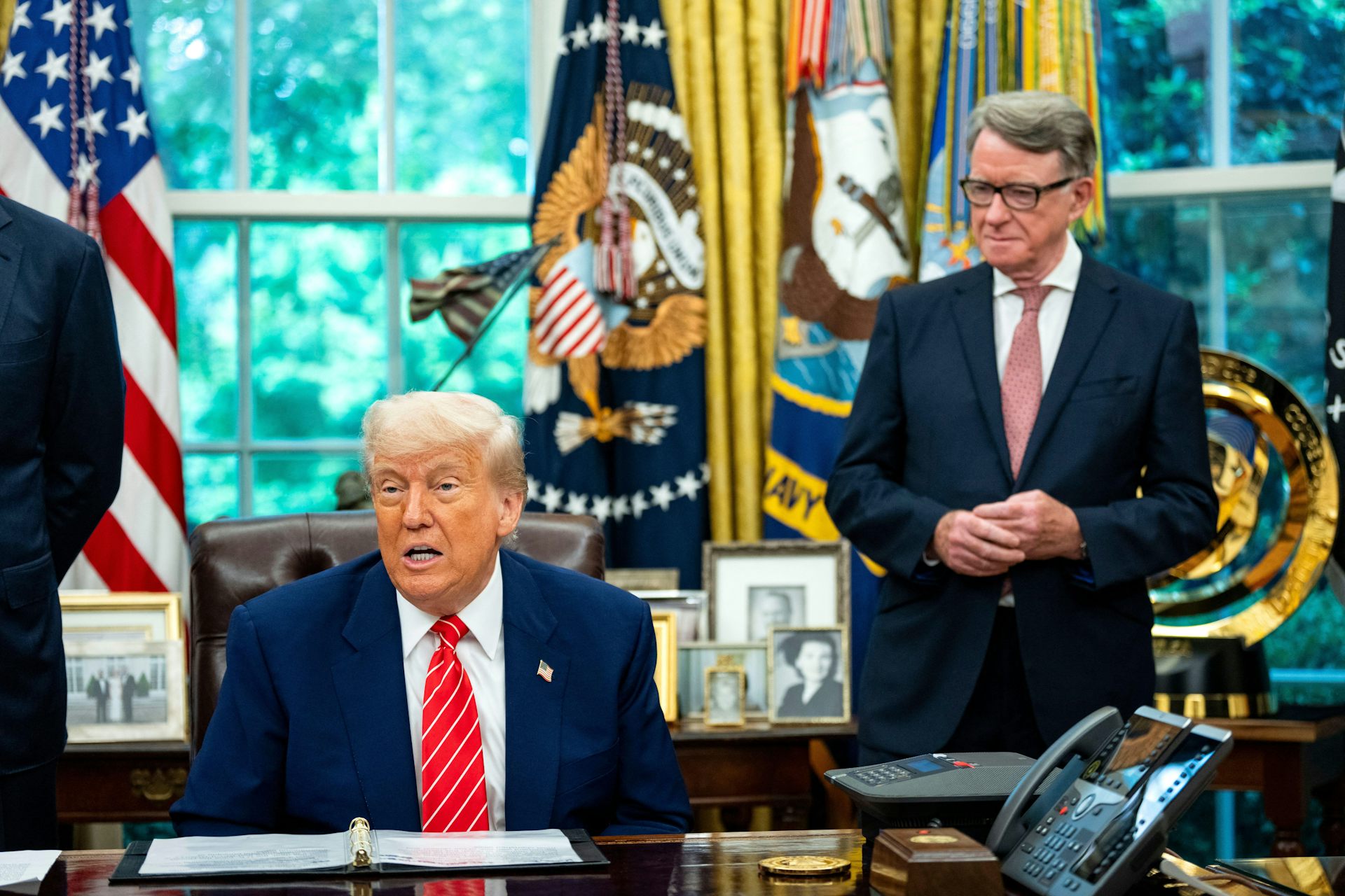 Peter Mandelson stands behind Donald Trump, who is seated at his desk in the Oval Office