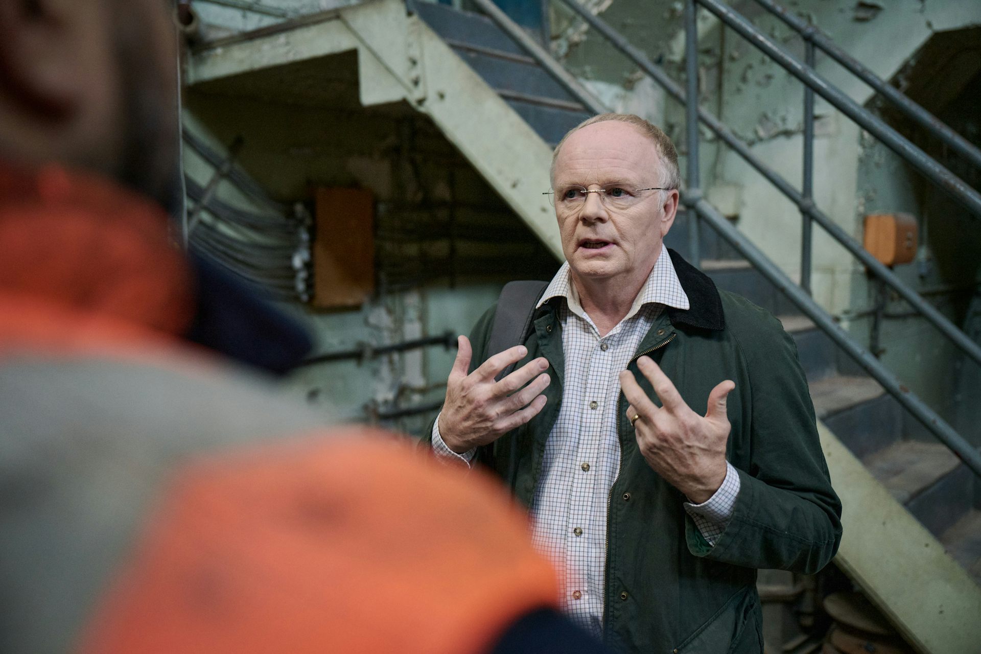 man in suit talks to another man in hi-vis