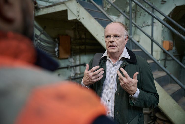 man in suit talks to another man in hi-vis