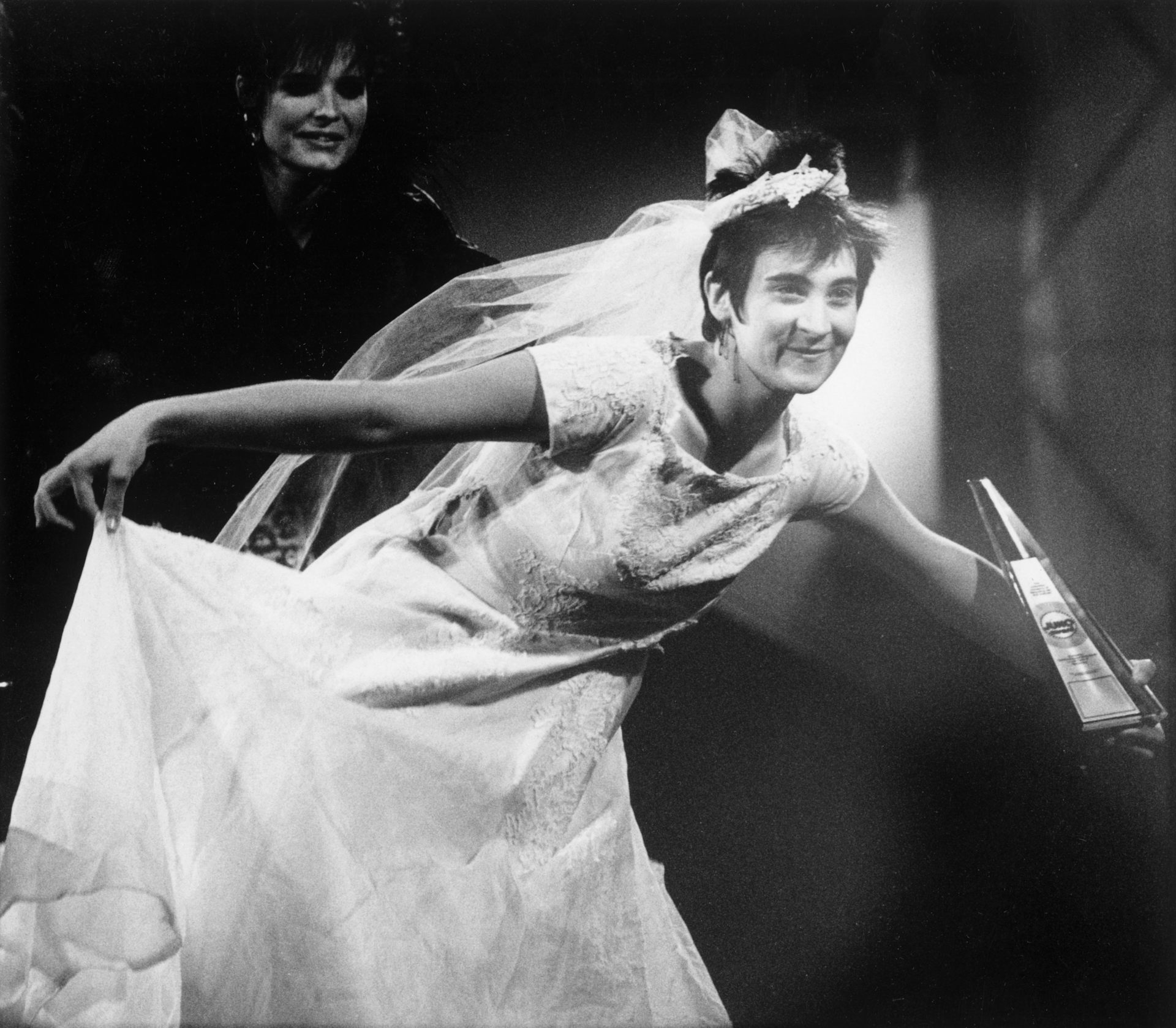 Una persona con un vestido de novia blanco en el podio de premios.