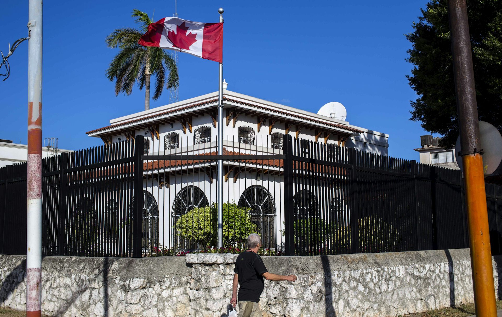 Un edificio blanco rodeado por una valla con una bandera canadiense en un poste
