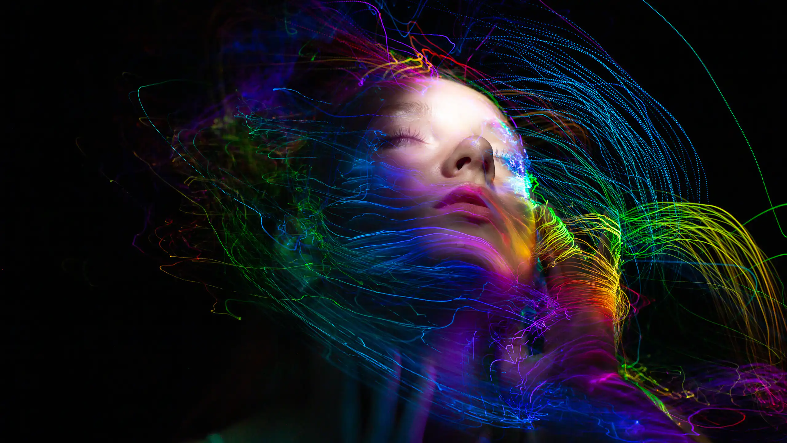 graphic of woman with eyes closed, colourful swirly lines on black background surround her