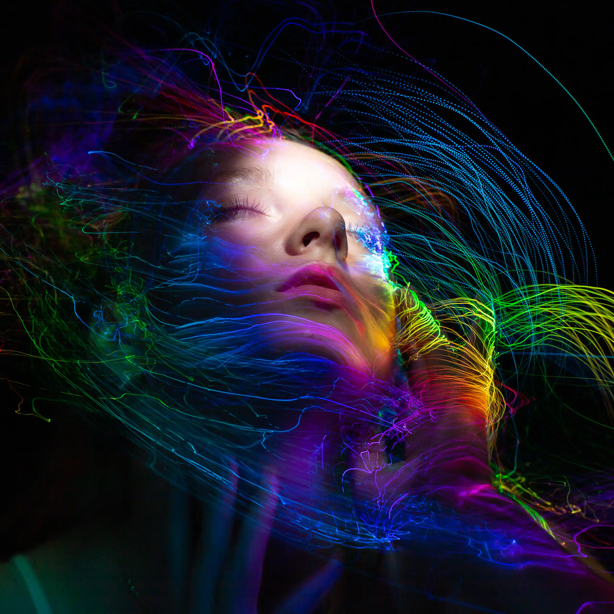 graphic of woman with eyes closed, colourful swirly lines on black background surround her