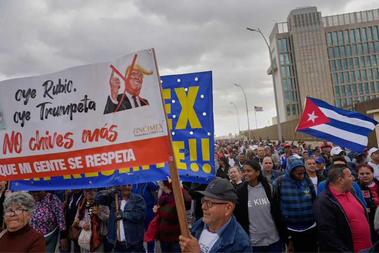People at a protest hold signs in spanish with a caricature of donald trump